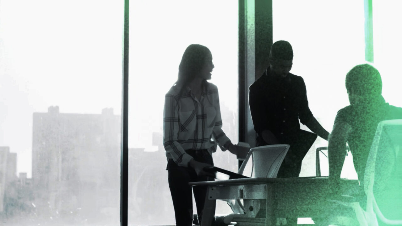 three people standing in a windowed office